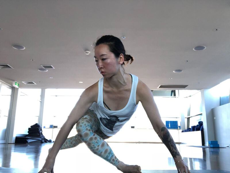 Cass in a low lunge on a yoga mat in a bright studio