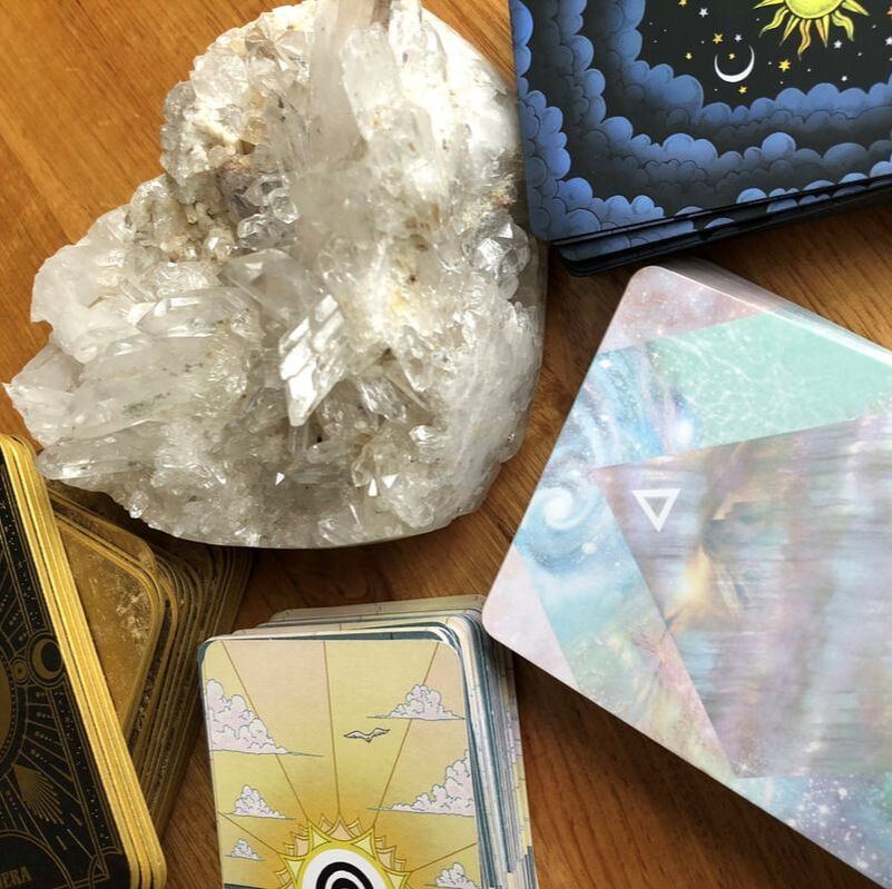 A large quartz crystal beside tarot and oracle card decks